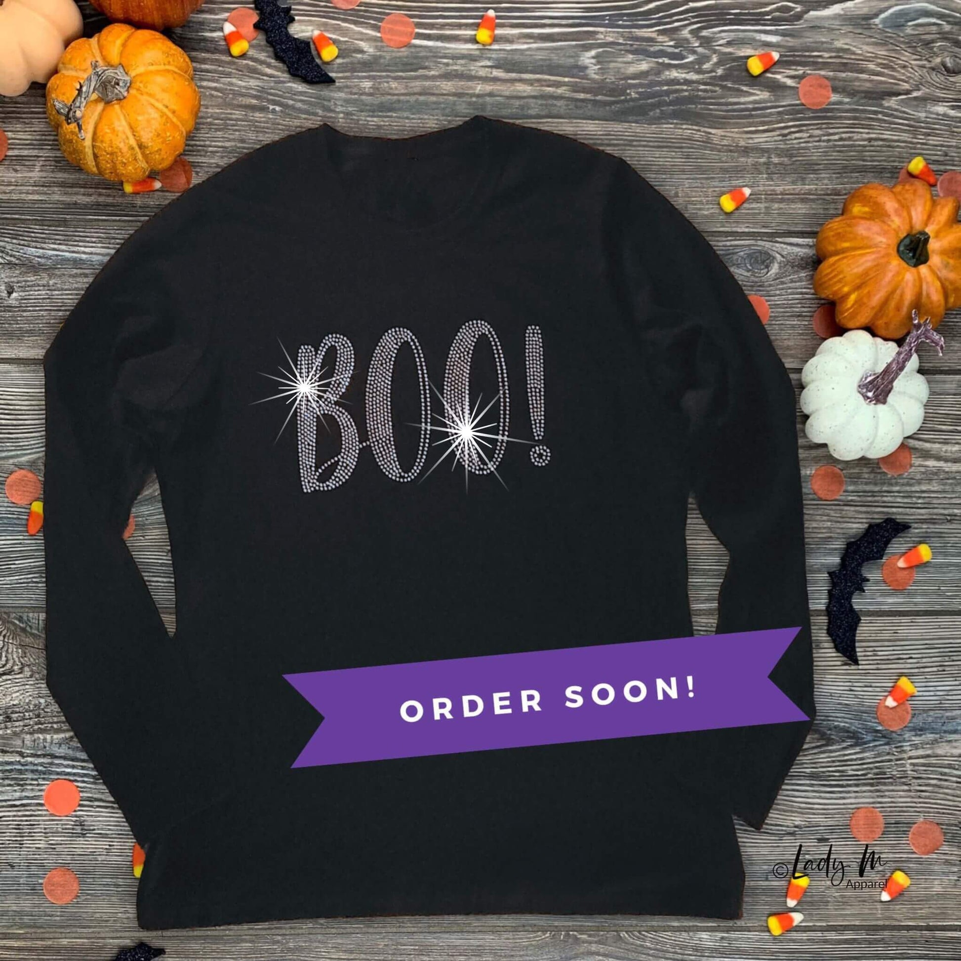 Women’s black long sleeve Halloween rhinestone shirt with sparkling “BOO!” design — festive bling tee with pumpkins and candy decor, order soon.