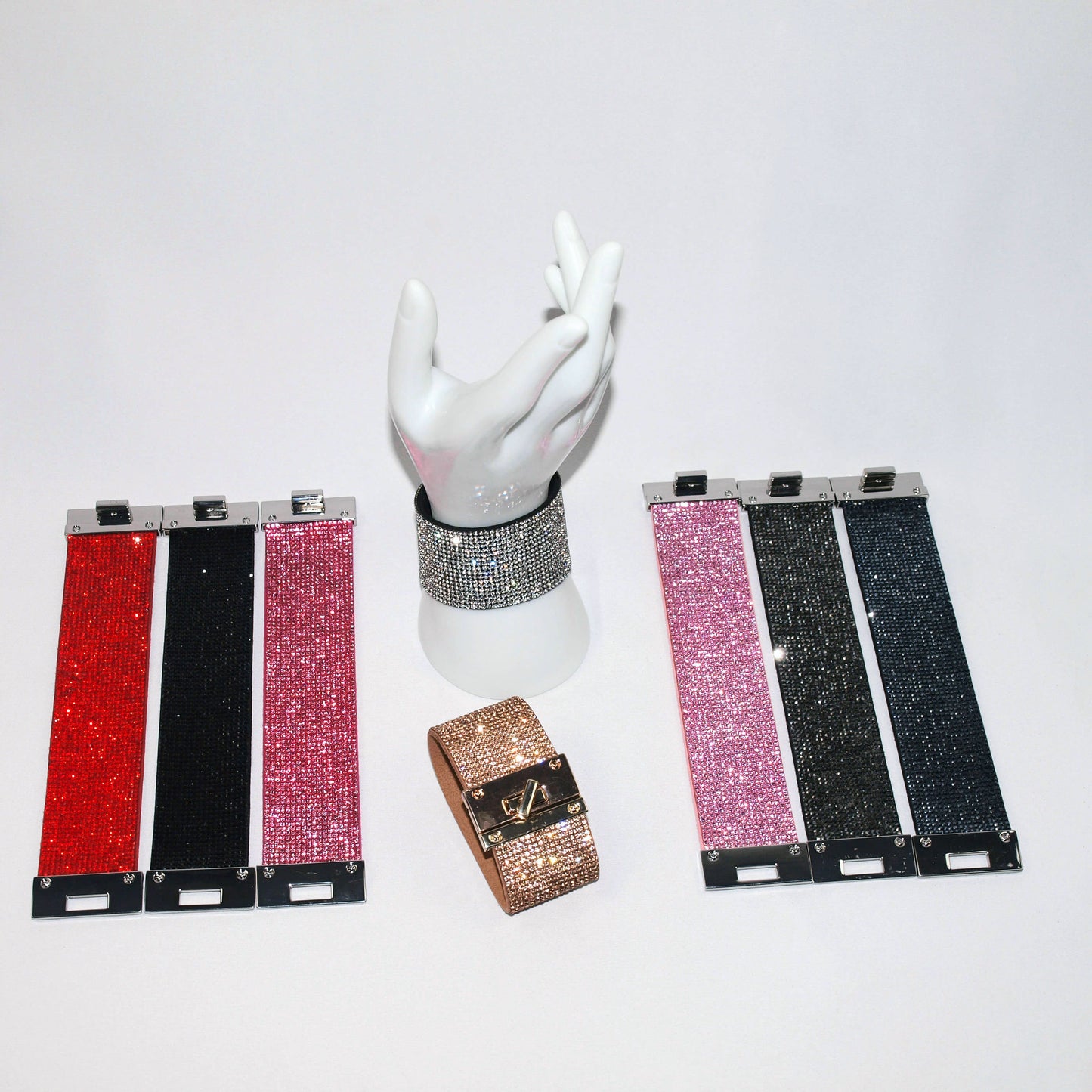 Wide rhinestone cuff bracelets in red, black, hot pink, rose gold, crystal, pink, off black, and ink displayed together